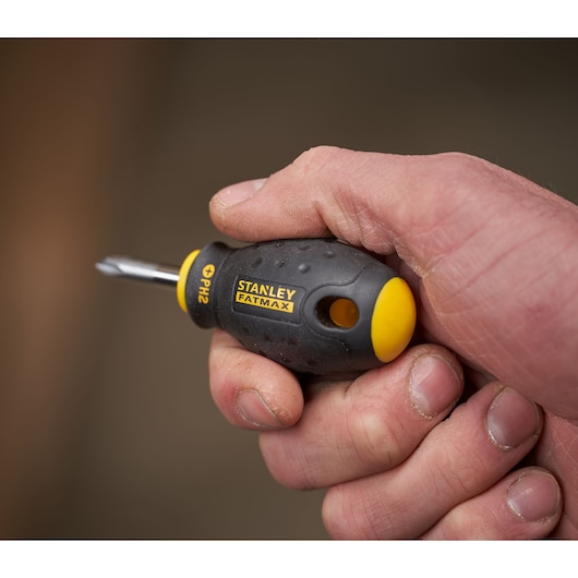 Stanley 0-65-407 stubby screwdriver with black and yellow FATMAX handle held in hand, PH2 tip visible.