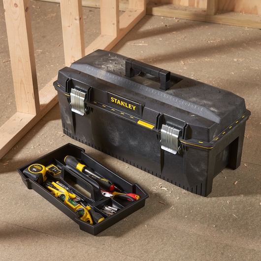 STANLEY 1-93-935 black toolbox with metal latches and removable tray filled with assorted tools in workshop.