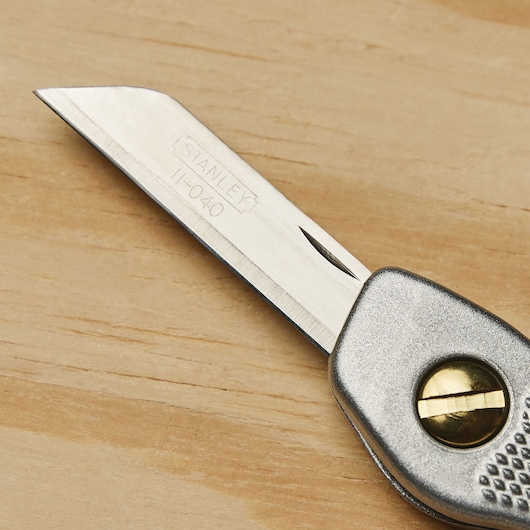 STANLEY 10-049 utility knife photography, close-up of silver blade and metallic handle on wood surface.
