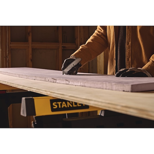Stanley 10-099 utility knife cutting foam board on workbench in workshop, close-up photo.