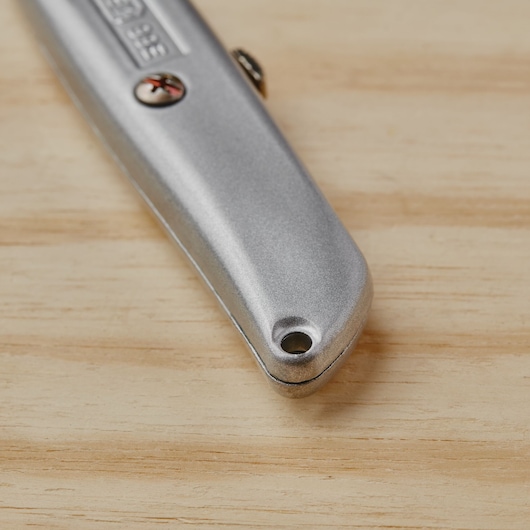 STANLEY 10-099 utility knife close-up, silver metal handle, partial view on wooden surface.