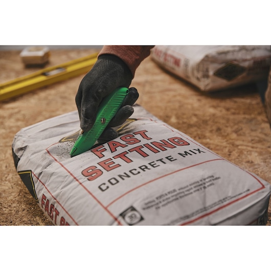 STANLEY 10-179 utility knife cutting open concrete mix bag, close-up photography.