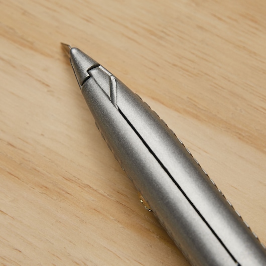 STANLEY 10-299 utility knife close-up on wood surface, showing metallic blade tip and textured gray handle.