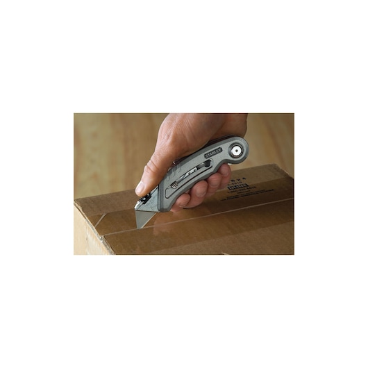 STANLEY 10-813 folding utility knife cutting cardboard box, handheld side angle.
