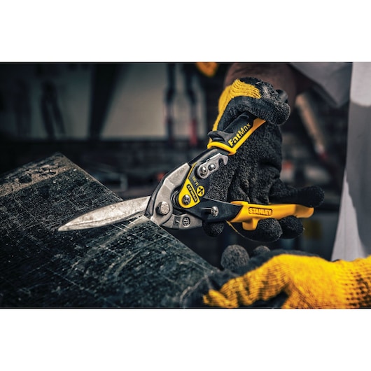 STANLEY 14-566 aviation snips with yellow and black handle cutting sheet metal, photographed in a workshop setting.