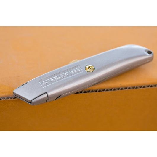 STANLEY 2-10-099 silver utility knife on cardboard, product side view.