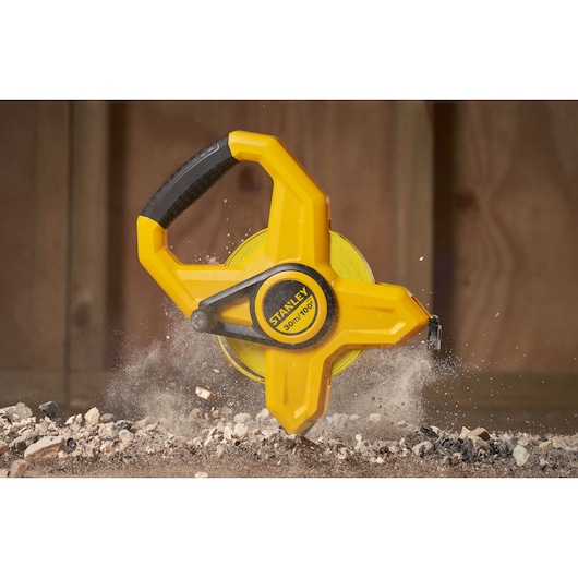 Photo of STANLEY 34-791 open reel yellow tape measure on construction debris, close-up side view.