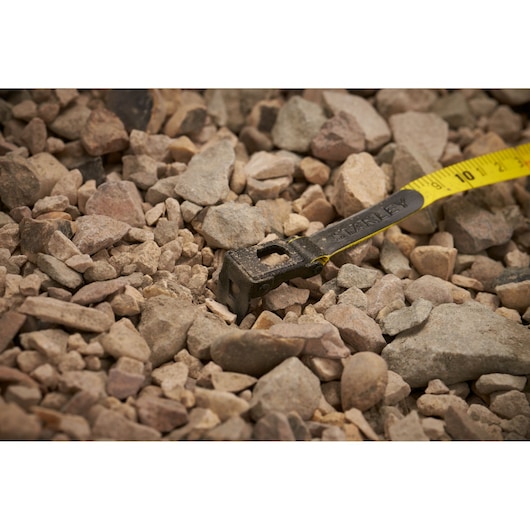 Stanley 34-791 tape measure with yellow blade extended on rocky ground, close-up photography.