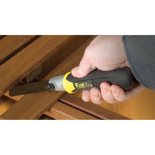 Stanley 20-220 FatMax hand saw in use cutting wood, close-up of ergonomic black and yellow handle.
