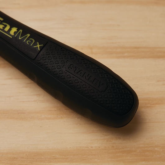STANLEY 20-220 hand saw handle close-up with black textured grip and FatMax logo, photographed on wood surface.