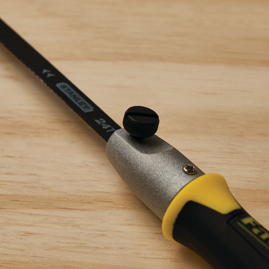 STANLEY 20-220 hand saw with black blade, yellow and black handle, close-up on wood surface.