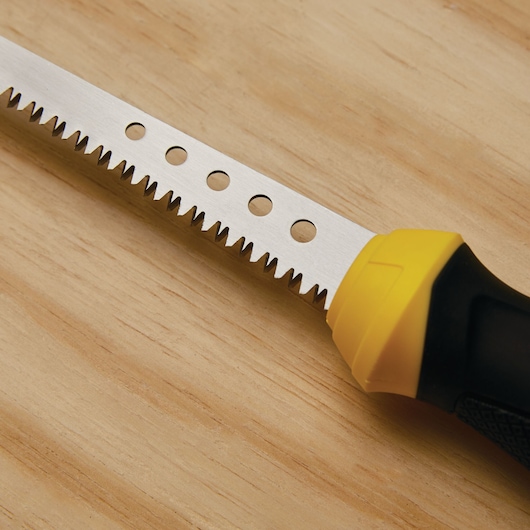 STANLEY 20-556 jab saw with sharp serrated blade, black and yellow handle, close-up on wood surface.