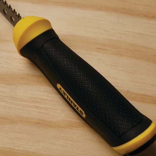 STANLEY 20-556 saw handle with black textured grip and yellow accents on wooden surface, close-up angle.