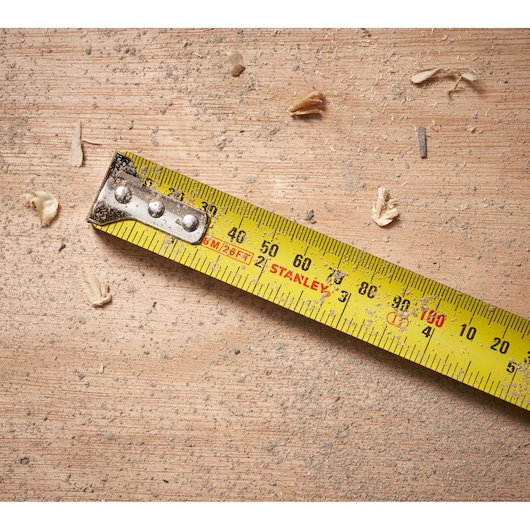 STANLEY 30-394 tape measure on dusty wood surface with wood shavings, top view photography.