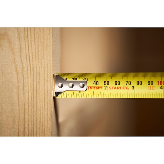 STANLEY 30-394 photography of yellow tape measure extended across wood surface, close-up side angle.