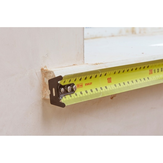 Photo of STANLEY 33-732 tape measure extended along a wall, yellow tape with clear metric markings.