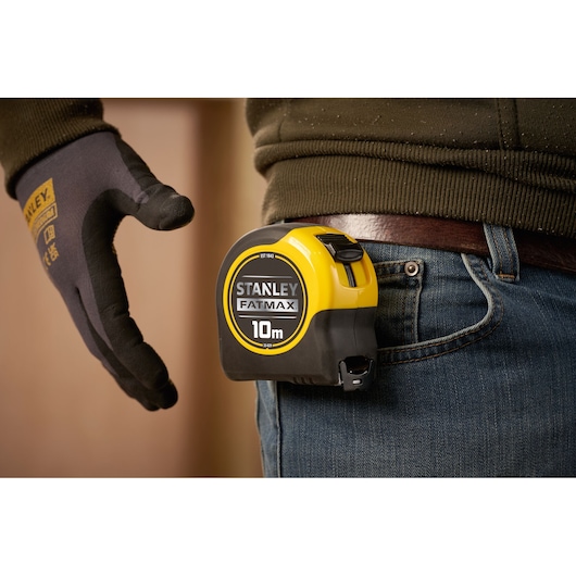 STANLEY 33-829 FATMAX 10m tape measure attached to belt, close-up side view.