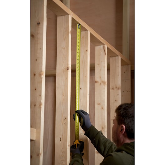 STANLEY 33-832 tape measure in use measuring vertical wooden frame, close-up photography.