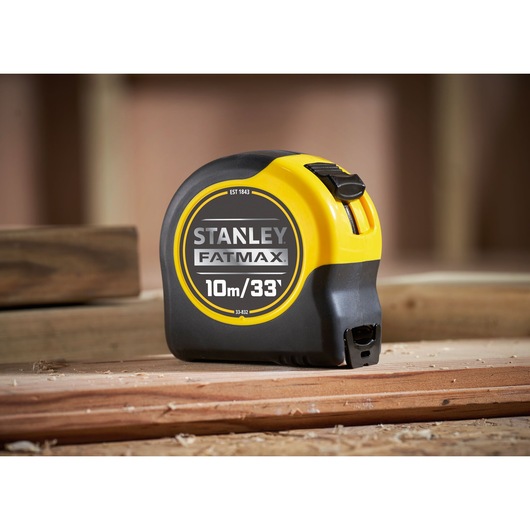 STANLEY 33-832 FatMax tape measure, black and yellow, photography, shown on wooden planks.