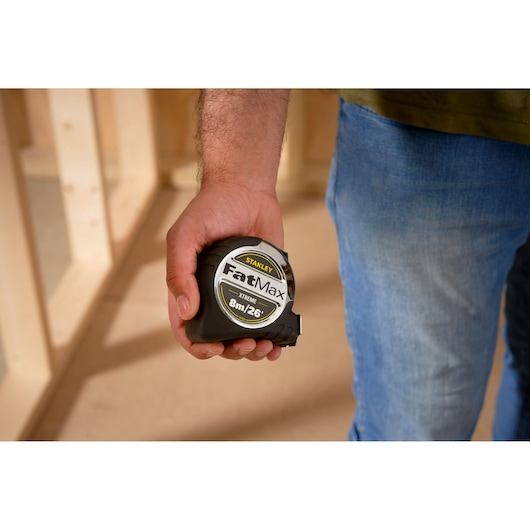 STANLEY 33-893 tape measure held in hand, FatMax branding, close-up indoor setting.