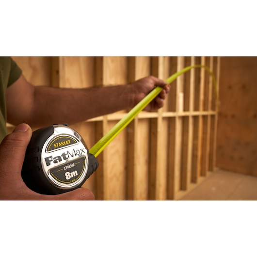 STANLEY 33-893 FatMax tape measure, 8m, being used in construction setting.