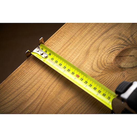 STANLEY 33-893 tape measure extended on wooden surface, close-up angle, yellow blade with black markings.
