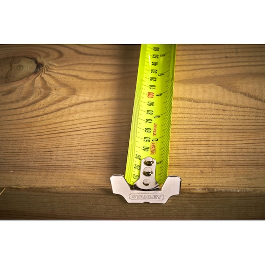 STANLEY 33-893 tape measure photography, yellow blade measuring wooden surface, close-up top view.