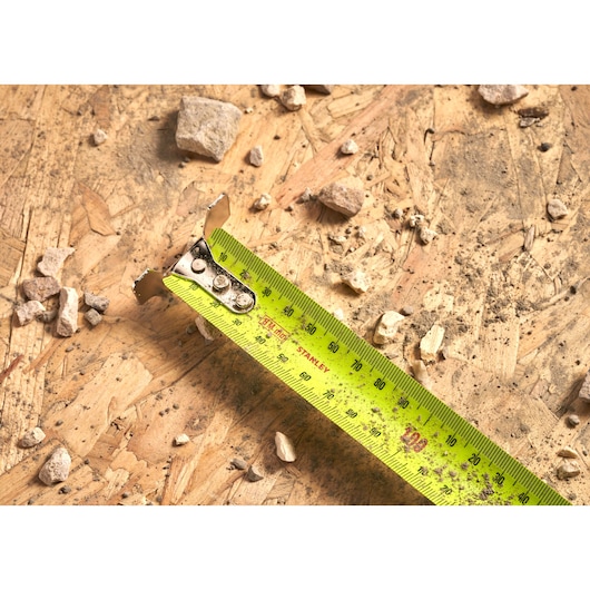 STANLEY 33-894 tape measure close-up on plywood with debris, showing measurement markings clearly.