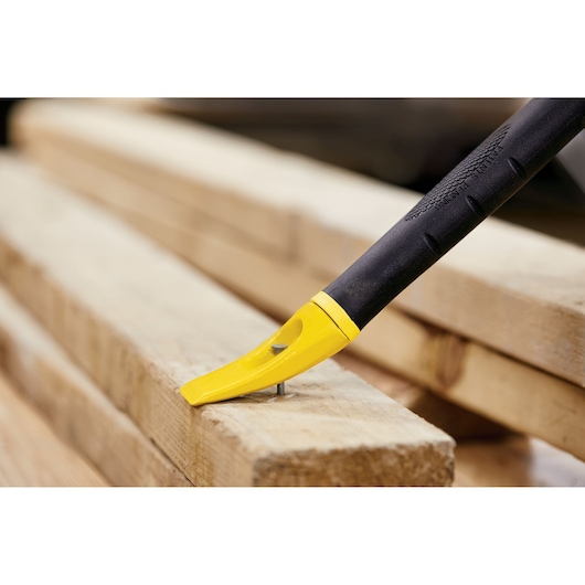 STANLEY 55-119 yellow and black pry bar removing nail from wood, close-up photography.