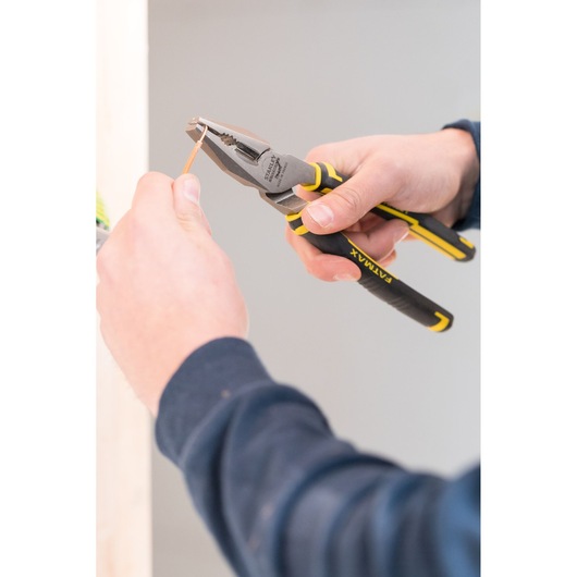 STANLEY 89-868 pliers with black and yellow grip, in use cutting copper wire, close-up.