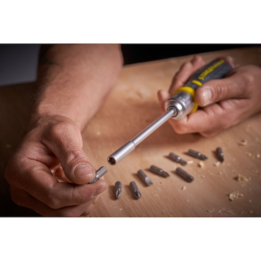 STANLEY FMHT0-62690 screwdriver with interchangeable bits, close-up showing hand inserting bit.