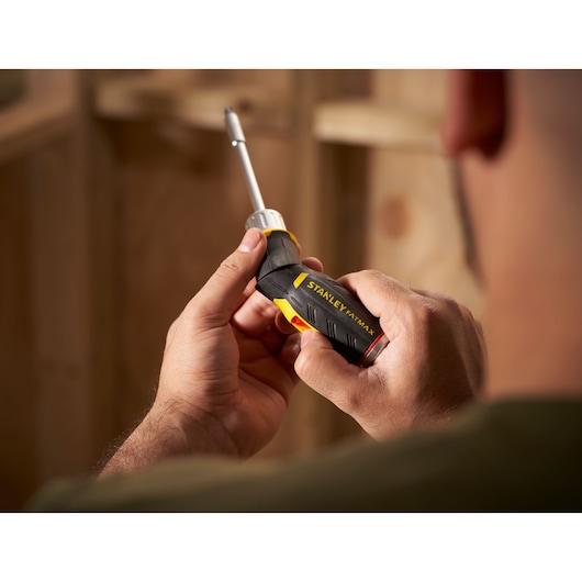 STANLEY FMHT0-62691 screwdriver with black and yellow handle held in hand, close-up side view.