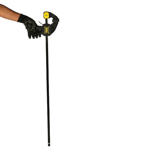 Photo of STANLEY FMHT0-83237 bar clamp held by a gloved hand, black and yellow clamp, front angle.
