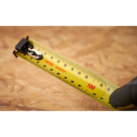 Photo of STANLEY FMHT33869 tape measure with yellow blade and clear metric markings, angled view.