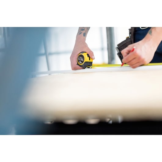 Photo of STANLEY FMHT36148-3 tape measure in use for marking measurements on a wooden surface.