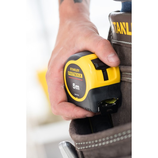 Photo of STANLEY FATMAX 5m tape measure, SKU FMHT36148-3, held in a tool belt pocket.