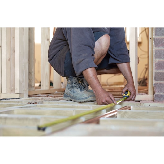 STANLEY FMHT36328 tape measure being used for floor framing in a construction setting.