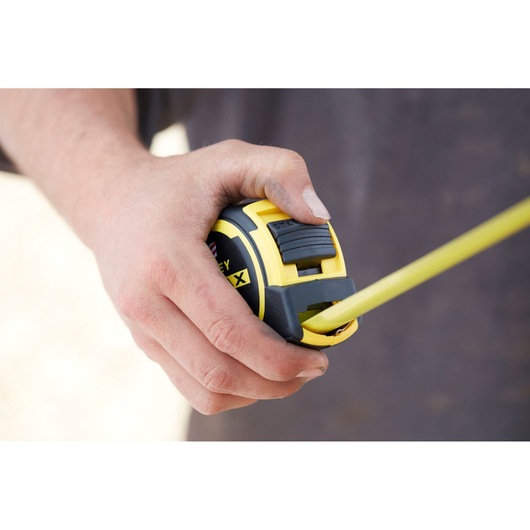 STANLEY FMHT36328 tape measure held in hand, close-up showing yellow and black casing.