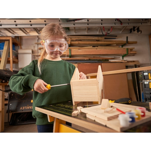 STANLEY K020-SY photography of child assembling wood birdhouse kit with screwdriver in workshop.