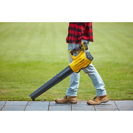 STANLEY SFMCBL7M1 cordless leaf blower shown in use on garden lawn.