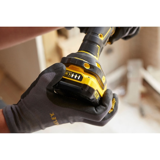 STANLEY SFMCD700D2S cordless drill close-up held by gloved hands, showing battery indicator in workshop.