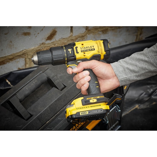 Stanley SFMCD711B cordless drill photographed in hand, yellow and black design, close-up view.