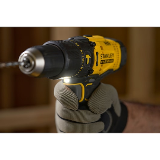 Photo of STANLEY SFMCD711B cordless drill with glove, yellow and black, in use indoors.