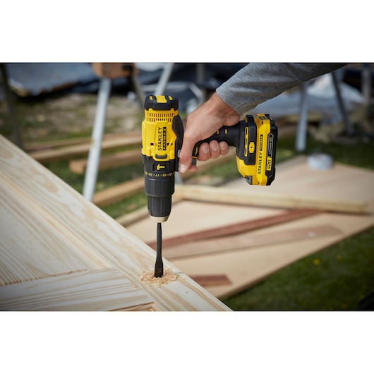 STANLEY SFMCD711B cordless drill being used on wood, close-up showing yellow and black tool.