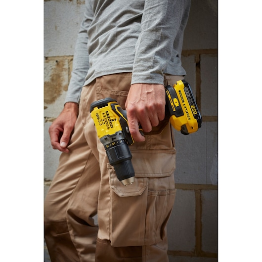 STANLEY SFMCD715D1A cordless drill driver held in right hand, side view, with yellow and black design.