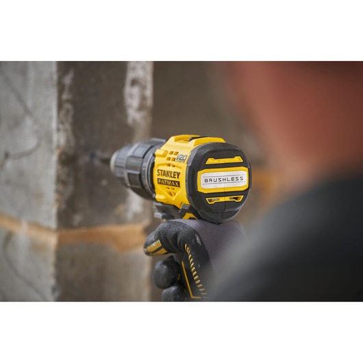 Photo of STANLEY SFMCD716B-XJ brushless drill in use against a concrete wall, focus on tool’s branding.
