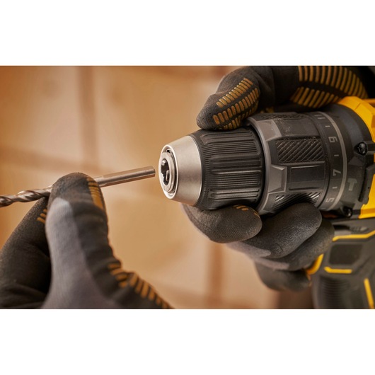 Stanley SFMCD716B-XJ drill close-up with gloved hand inserting a drill bit.