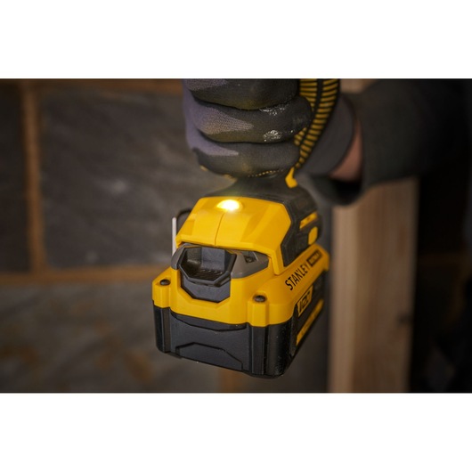 STANLEY SFMCD716B-XJ cordless drill close-up in hand, yellow and black, LED light on, indoor setting.