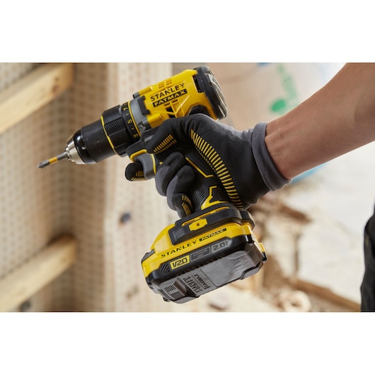 Photo of STANLEY SFMCD720DR2 cordless drill driver in use, yellow and black design in worksite setting.