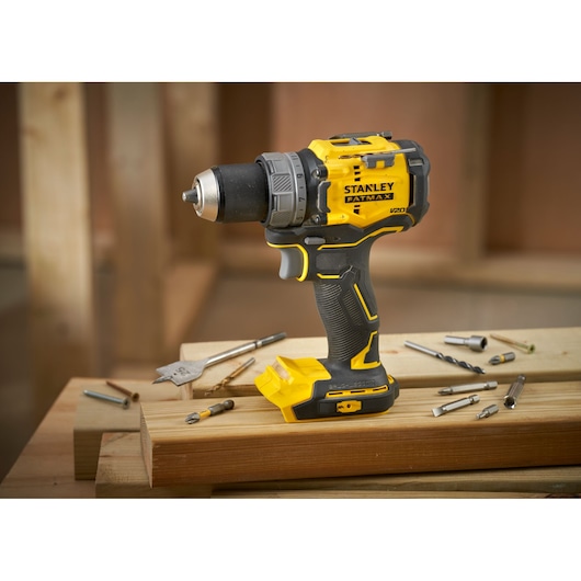STANLEY SFMCD725D2K cordless drill, yellow-black, side view, on wood with drill bits.